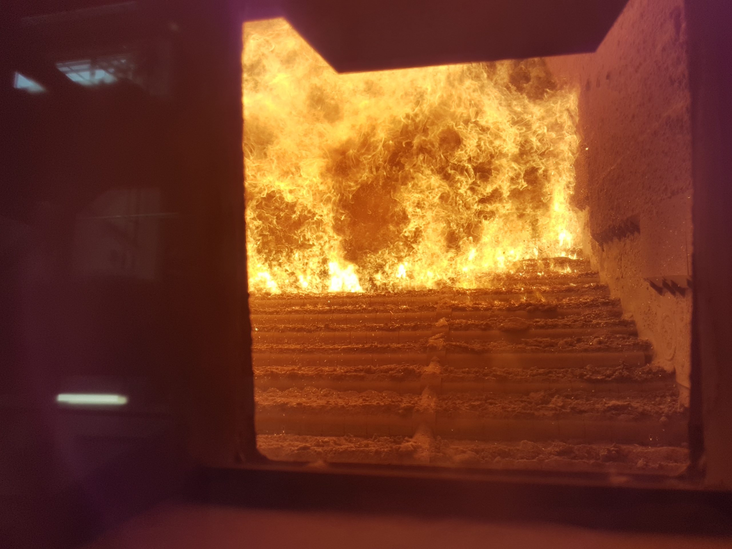 Close-up of the combustion chamber inside an industrial biomass boiler, showing the fuel intake system and burner elements