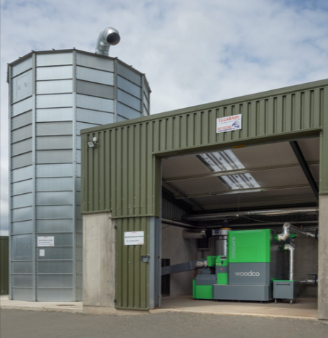 Large-scale wood chip heating system in an industrial setting, with interconnected boilers, fuel silos, and automated feed systems