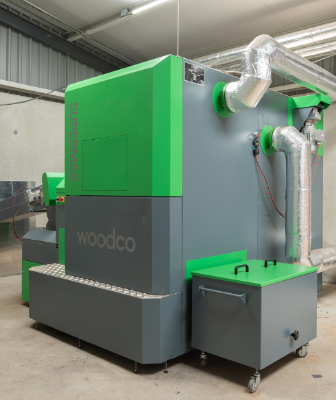 A Woodco SuperMax biomass boiler system installed in a commercial building, featuring advanced technology for efficient wood chip and pellet heating