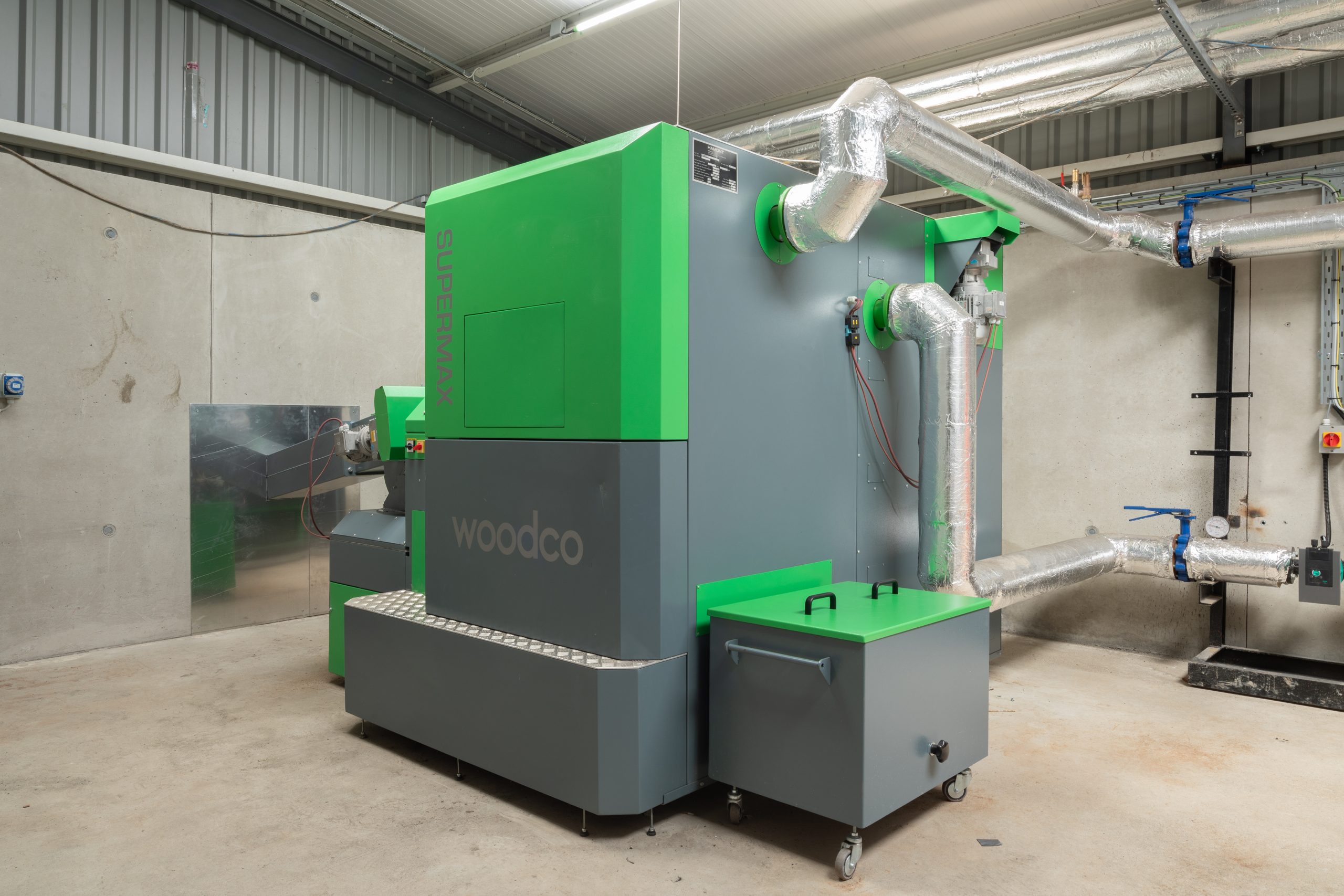 Woodco biomass boiler being installed in a commercial plant room with insulated pipework